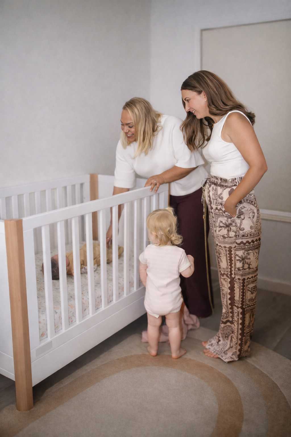 Family moment with mothers and children around a crib